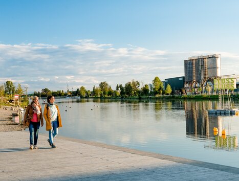 Two women walk along the riverbank - at sunset in Graz. | © Graz Tourismus