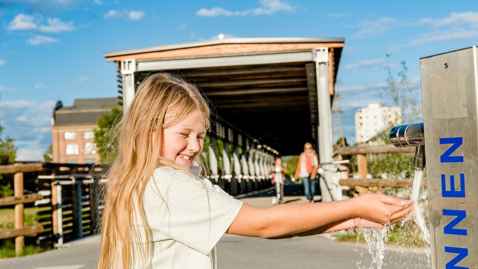 A child playing with water at a drinking fountain in Graz. | © Graz Tourismus