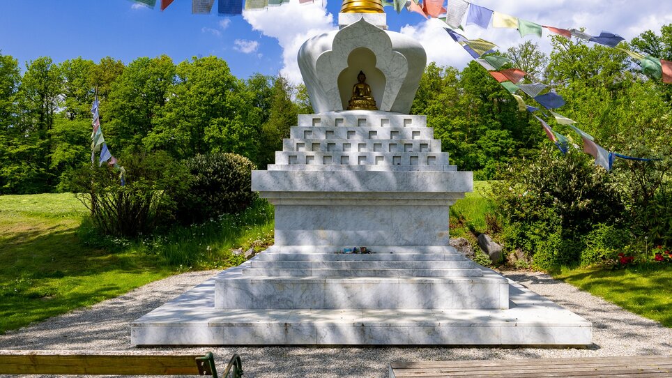 Stupa in nature with prayer flags, peaceful surroundings. | © Graz Tourismus