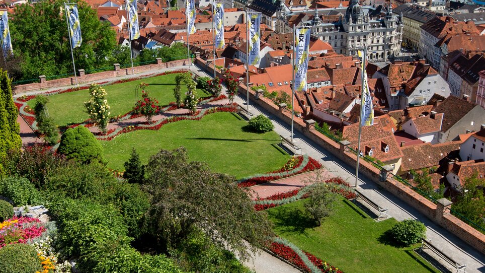 Der Herbersteingarten mit blühenden Pflanzen am Grazer Schlosberg mit Blick auf die Stadt und das Rathaus. | © Graztourismus - Harry Schiffer