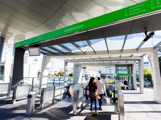 Modernes Bahnhofseingangsgebäude in Graz mit Fahrkartenautomaten und Passagieren. | © Graz Tourismus - Harry Schiffer