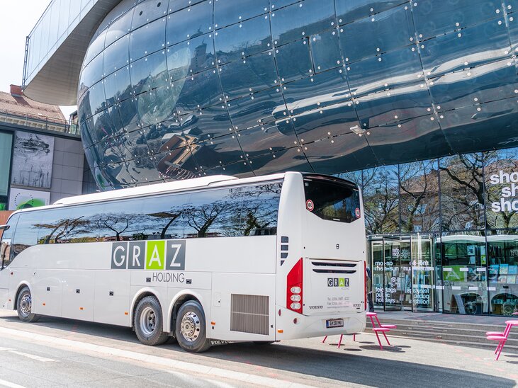A Graz Holding bus is parked in front of the Kunsthaus Graz in the city of Graz. | © achtzigzehn - Hinterleitner