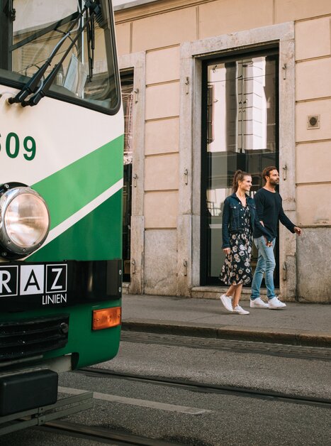 A couple casually walks past a tram in Graz. | © Graz Tourismus