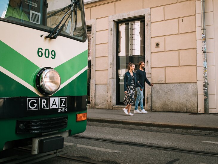 A couple casually walks past a tram in Graz. | © Graz Tourismus