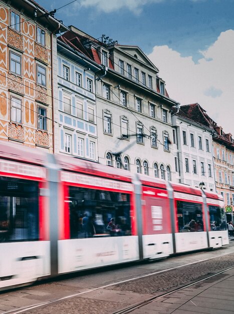 Un tram a Graz passa davanti a una facciata colorata in Piazza Principale. Sullo sfondo si vede il negozio Swarovski. | © Janet Newenham-Journalist on the Run