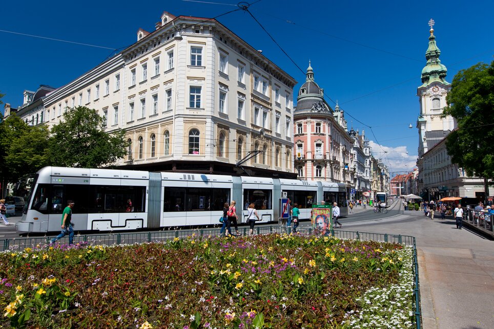 Fiori colorati e un tram a Graz in una giornata di sole. | © Graz Tourismus - Harry Schiffer