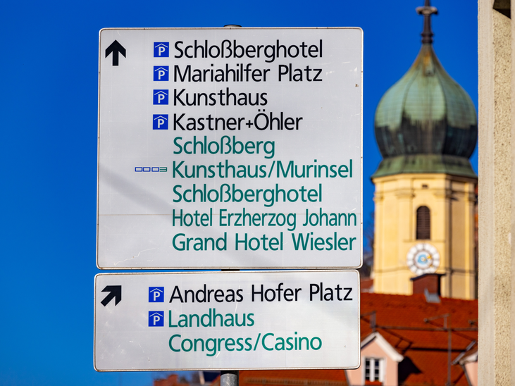The image shows a signpost in Graz indicating various destinations, including hotels and squares. | © Graz Tourismus - Harry Schiffer