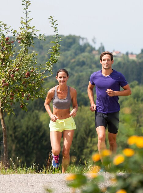 Aktives Paar joggt auf einem Weg umgeben von Bäumen in der Natur von Graz | © Region Graz - Tom Lamm