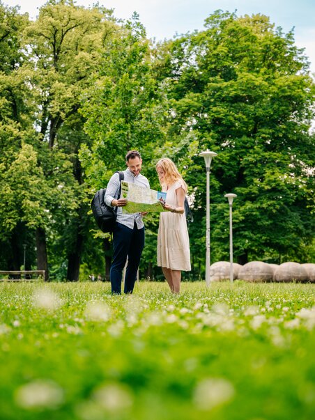 Couple stands in Augarten, looking at a map. | © Graz Tourismus - Mias Photoart
