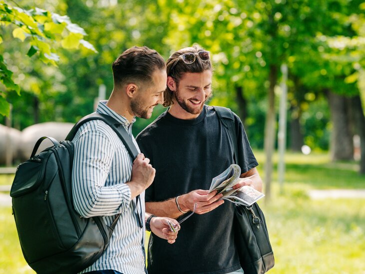 Zwei Männer im Augarten in Graz schauen sich eine Karte an. | © Graz Tourismus - Mias Photoart