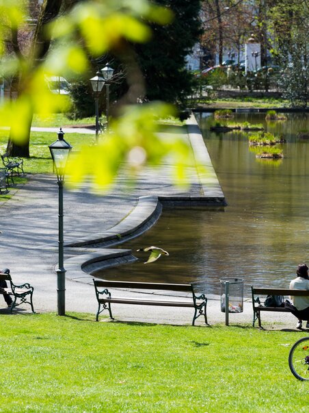 A peaceful city park in Graz with benches and a water feature. | © Graz Tourismus - Harry Schiffer