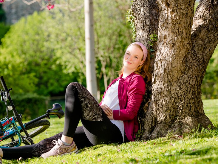 Eine Frau sitzt an einen Baum gelehnt im Grünen mit einem Fahrrad in Graz. | © Mias Photoart
