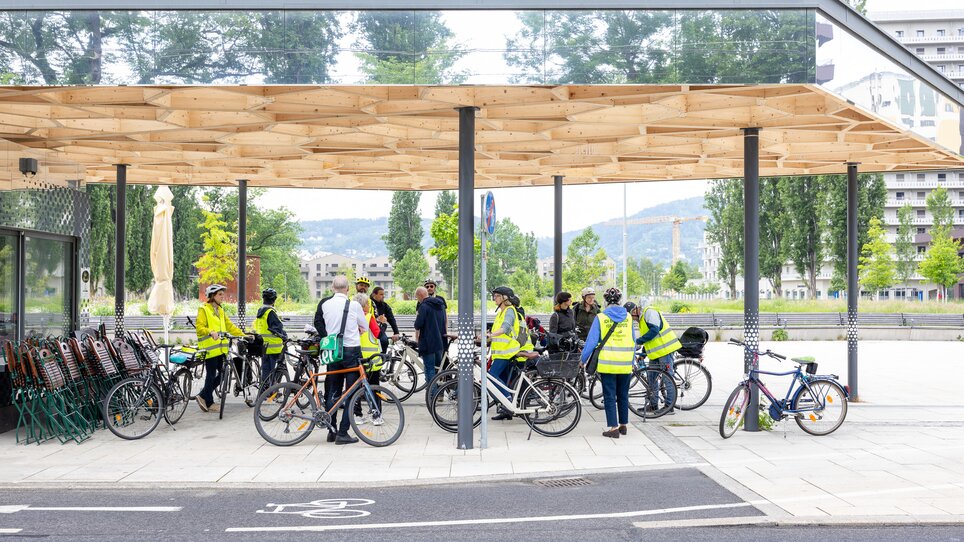 Radfahrer versammeln sich unter einer modernen Überdachung in Graz. | © Graz Tourismus - Harry Schiffer
