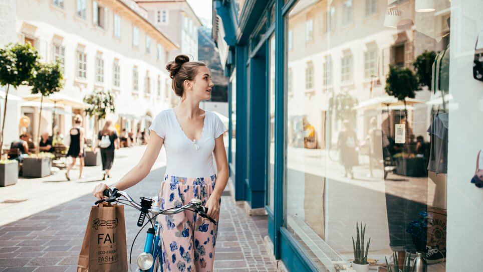Eine Frau in Graz schaut in ein Schaufenster und hält eine Einkaufstüte. | © Graz Tourismus