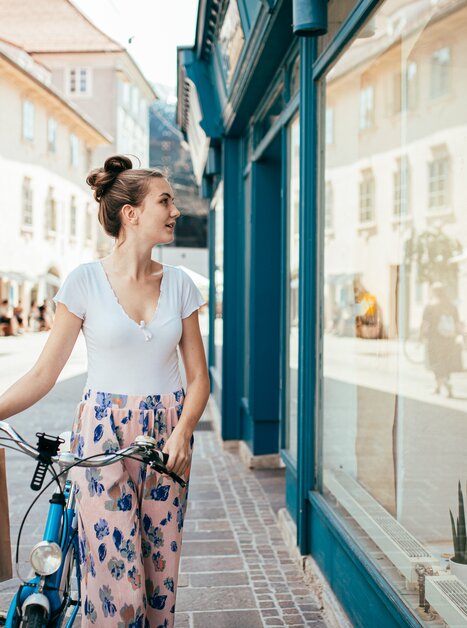 A woman in Graz looks into a shop window while holding a shopping bag. | © Graz Tourismus