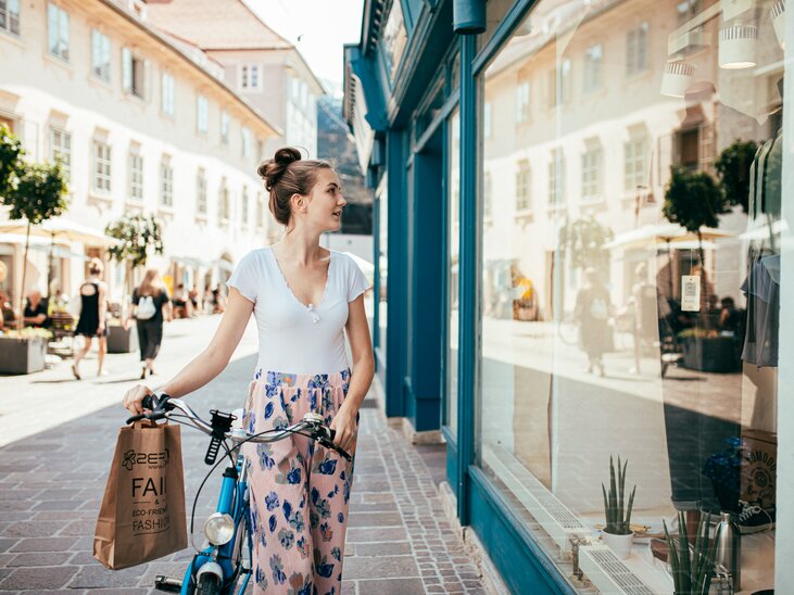 Eine Frau in Graz schaut in ein Schaufenster und hält eine Einkaufstüte. | © Graz Tourismus