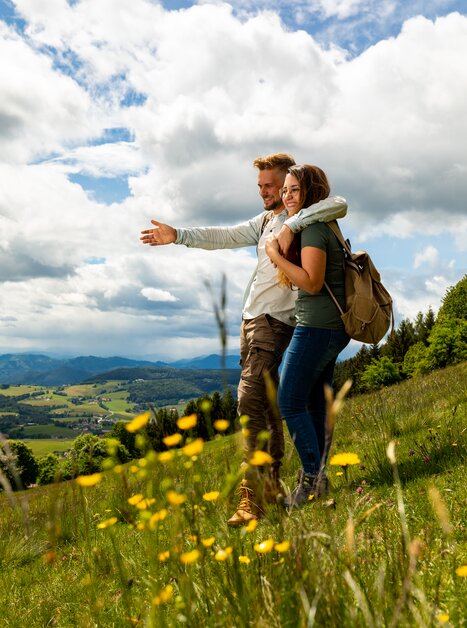 Ein Paar genießt die Aussicht in der Natur, umarmt und lächelt. | © Region Graz - Harry Schiffer