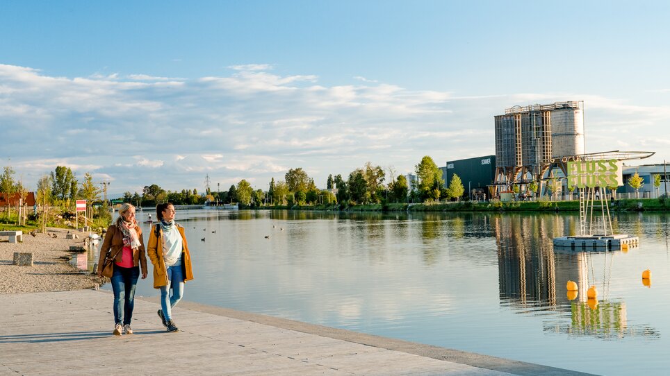 Zwei Freundinnen spazieren entlang der Mur beim Stadtstrand in Graz. | © Graz Tourismus - Mias Photoart
