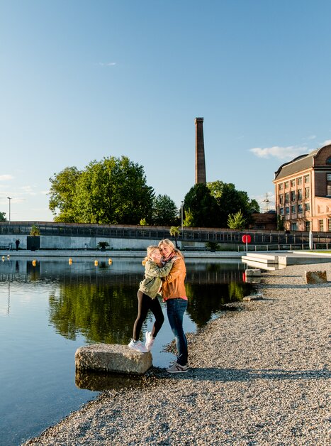 Mutter und Tochter umarmen sich am Ufer der Mur beim Stadtstrand in Graz bei Sonnenuntergang. | © Graz Tourismus - Mias Photoart