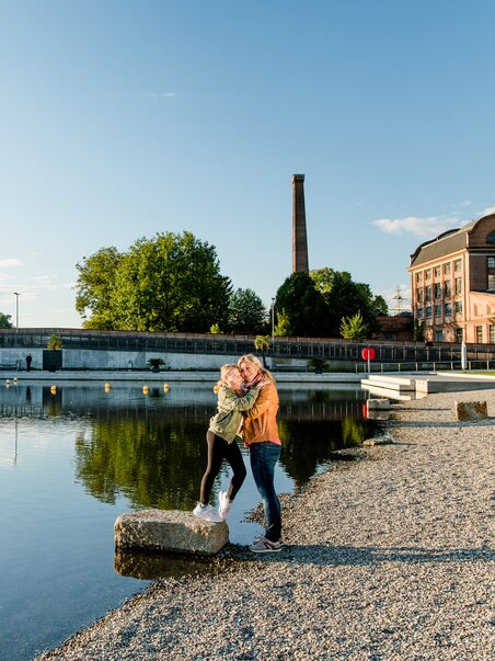 Mother and daughter embrace on the banks of the Mur at the Stadtstrand in Graz during sunset. | © Graz Tourismus - Mias Photoart