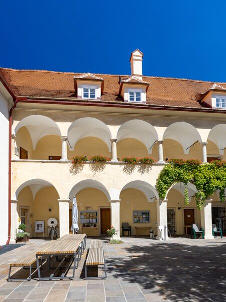 Courtyard with arches and trees, bright blue sky. | © Graz Tourismus - Harry Schiffer