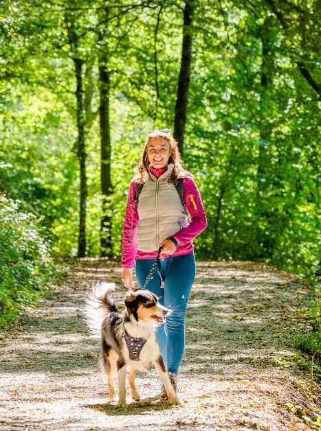 Eine Frau geht mit ihrem Hund auf einem Waldweg in Graz. | © Graz Tourismus - Mias Photoart-28