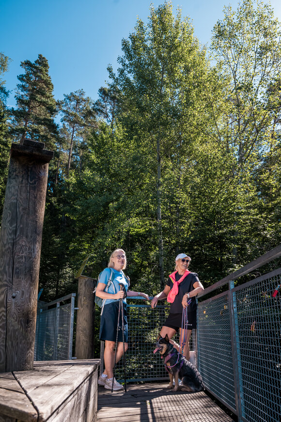 Zwei Personen mit Hund auf Brücke in der Natur. | © Graz Tourismus - Mias Photoart