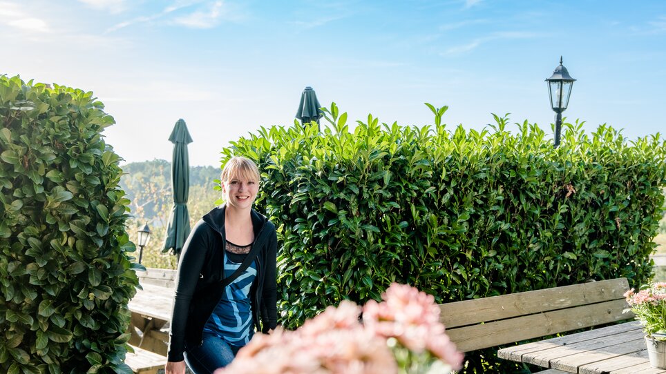 A smiling woman outdoors, surrounded by plants and flowers. | © Graz Tourismus - Mias Photoart