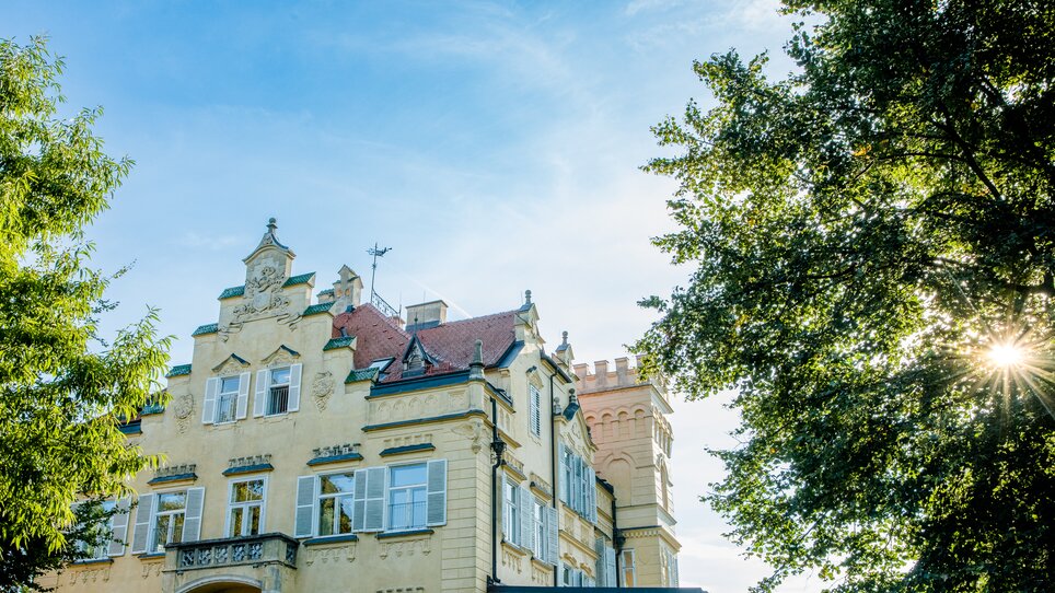 Schloss Lustbühel with towers and trees under a bright sky in Graz. | © Graz Tourismus - Mias Photoart