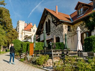 Idyllic scene with a traditional wine tavern (Buschenschank) and Schloss Lustbühel in the background. | © Graz Tourismus - Mias Photoart