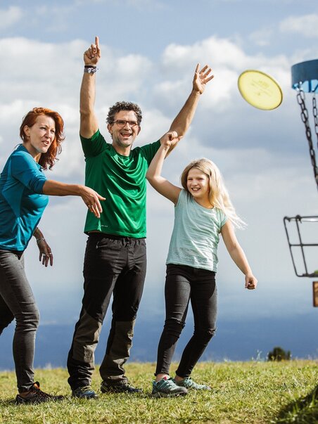 Fröhliche Familie spielt Frisbee-Disc Golf am Schöckl in Graz. | © Holding Graz - Lex Karelly