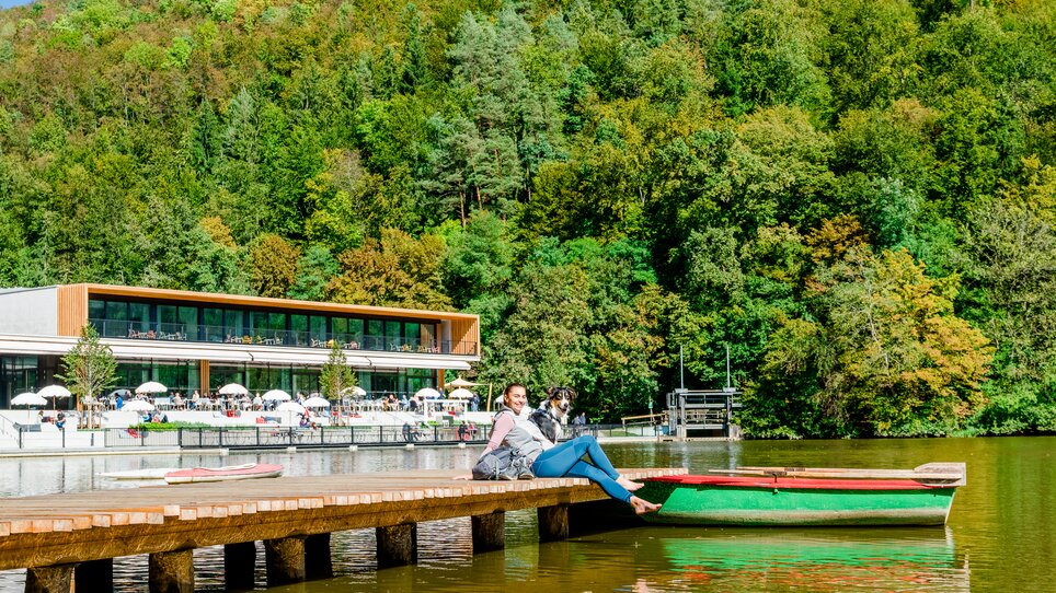 Eine Frau sitzt am Steg am Thalersee mit ihrem Hund. | © Graz Tourismus - Mias Photoart