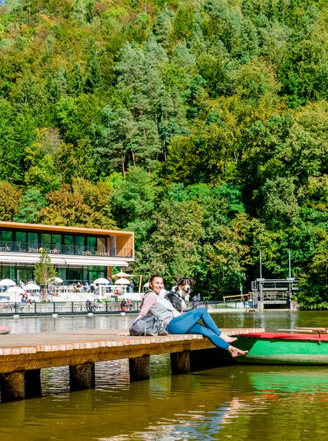 Eine Frau sitzt am Steg am Thalersee mit ihrem Hund. | © Graz Tourismus - Mias Photoart