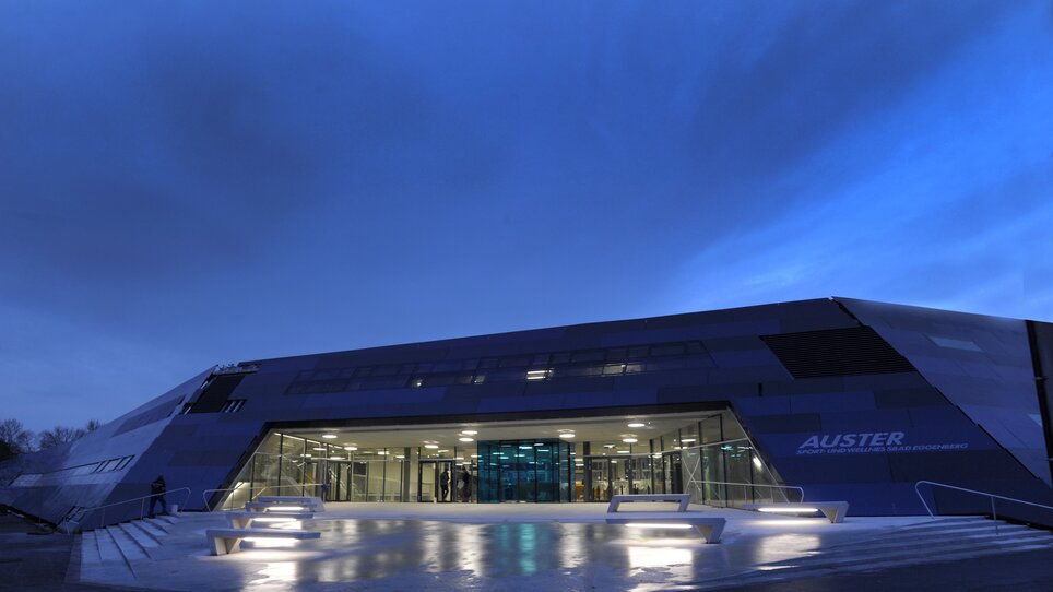 Futuristic swimming pool building Auster in Graz at dusk. | © Holding Graz - Helge Sommer