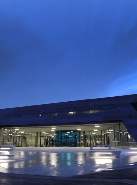 Futuristisches Schwimmbadgebäude Auster in Graz bei Dämmerung. | © Holding Graz - Helge Sommer