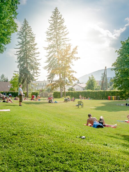 Visitatori godono di una giornata di sole allo Stukitzbad di Graz sull'erba. | © Holding Graz - Joel Kernasenko