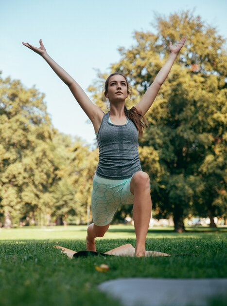 Woman practicing yoga in a park, with arms raised. | © Graz Tourismus