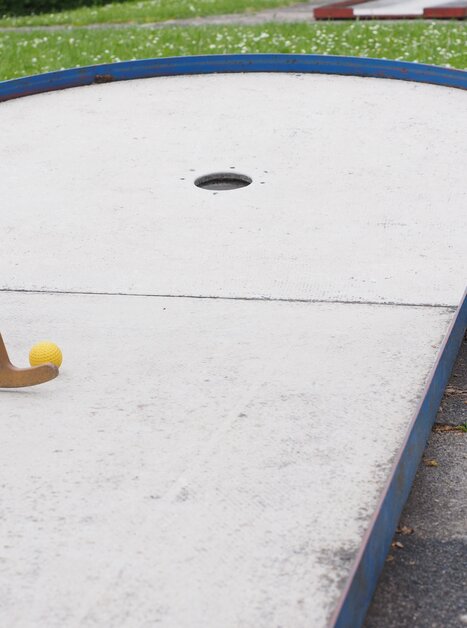 Close-up of a mini golf course featuring a yellow ball and a wooden club. | © Pixabay