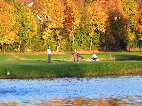Golfers on a putting green surrounded by colorful autumn trees. | © GEPA-pictures - Murhof Gruppe