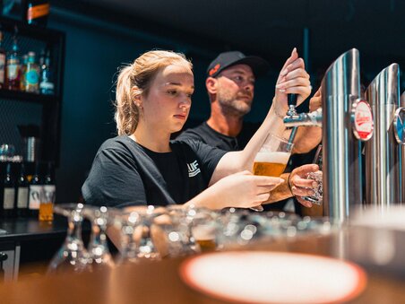 Zwei Personen zapfen Bier an der Bar, eine Frau und ein Mann. | © GEPA I RUFF Golf Graz
