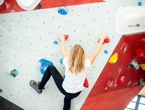 Ein Jugendlicher klettert an einer bunten Boulderwand. | © pixapay