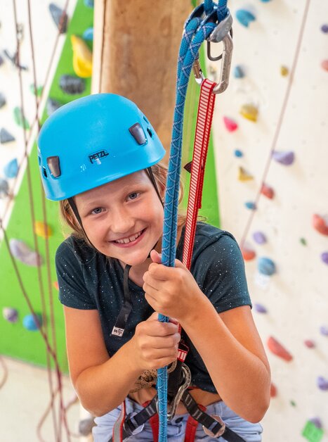 A smiling child wearing a blue helmet while climbing. | © C-A-C