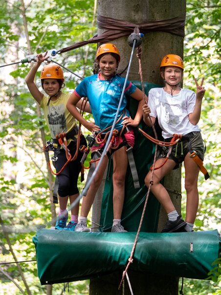 Drei Kinder im Kletterwald mit Sicherheitsausrüstung und Helmen. | © WAP