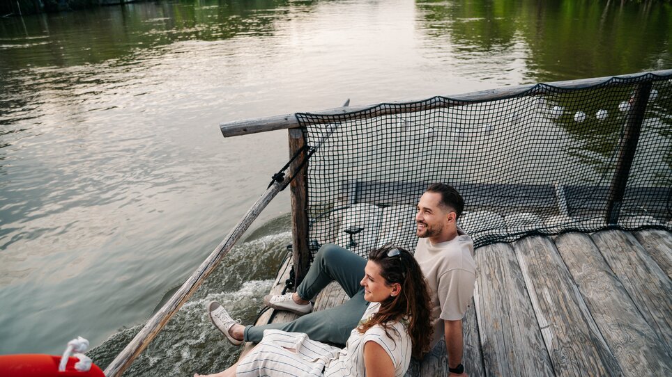 Couple sitting by the river enjoying the view while rafting. | © Graz Tourismus - Mias Photoart