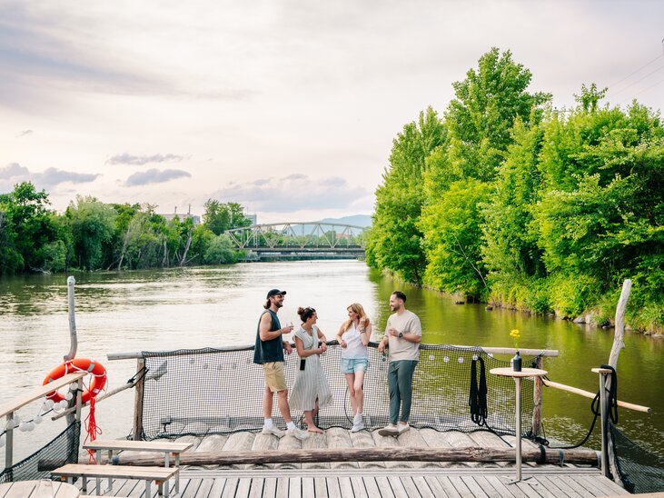 Group of friends enjoying time by the river in Graz, surrounded by trees. | © Graz Tourismus - Mias Photoart