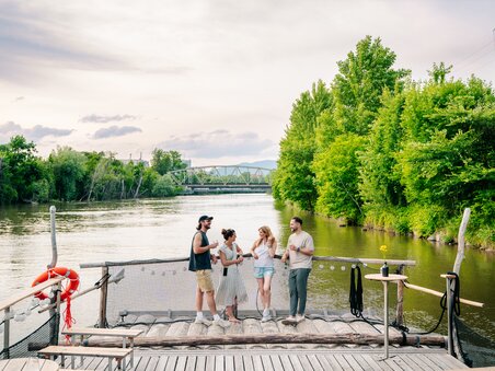 Gruppe von Freunden genießt Zeit am Fluss in Graz, umgeben von Bäumen. | © Graz Tourismus - Mias Photoart