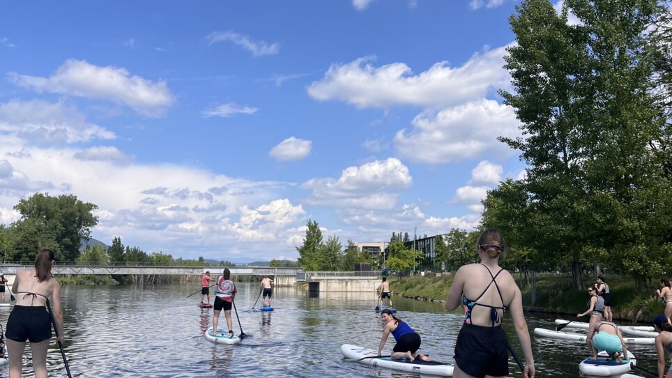 Gruppe von Menschen beim Stand-Up-Paddling auf einem ruhigen Gewässer mit blauem Himmel. | © Die Flößerei