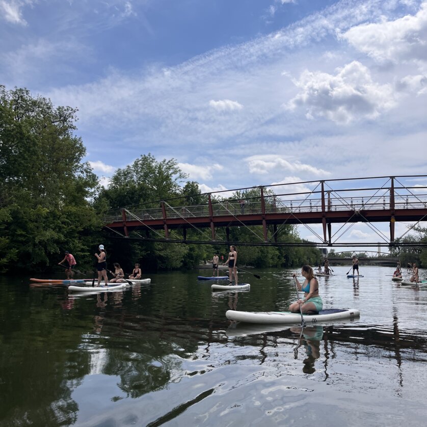 Paddler auf der Mur in Graz vor einer Brücke an einem sonnigen Tag. | © Die Flößerei