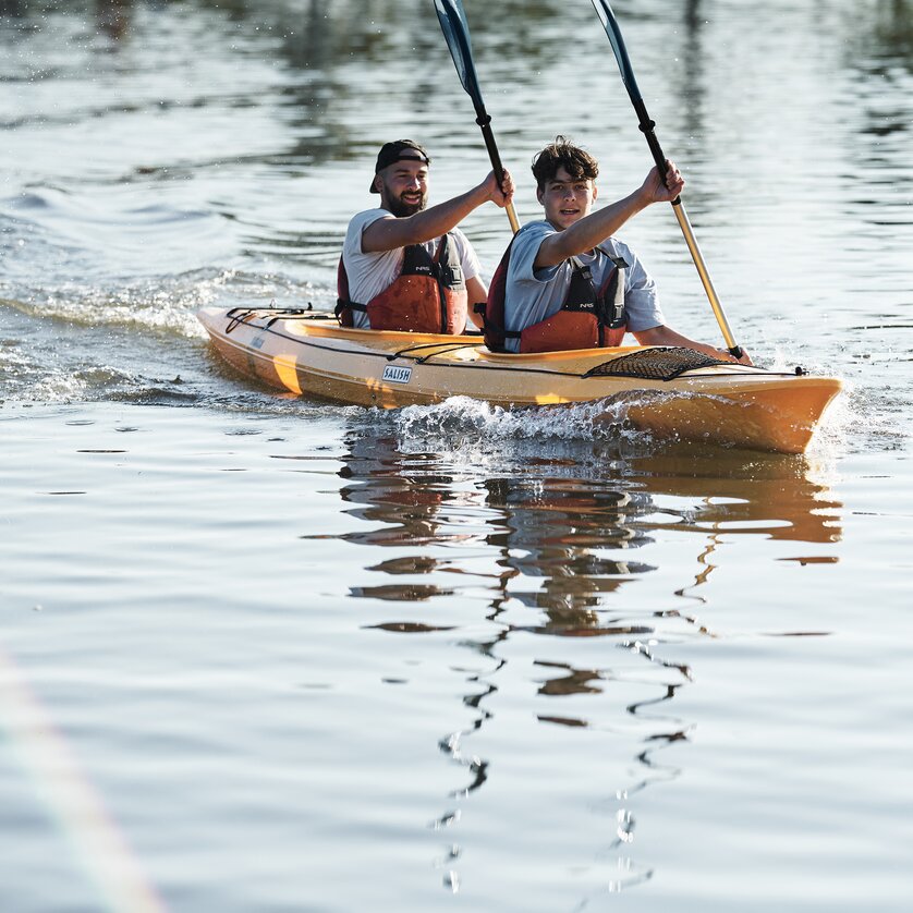 Two people joyfully paddling in a kayak on calm water. | © Stefan Leitner