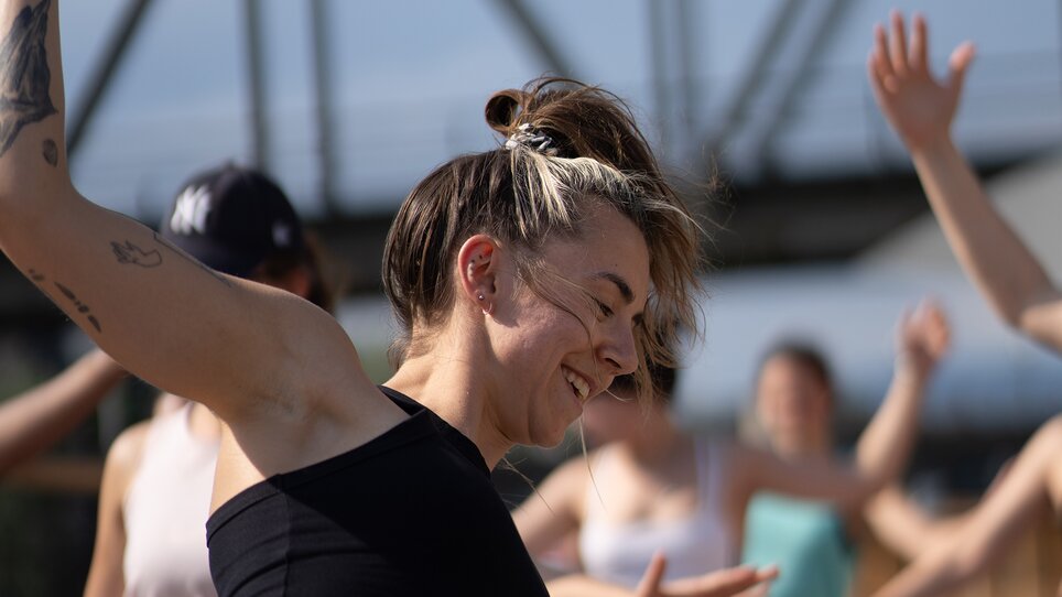 Un gruppo di persone partecipa a un corso di yoga su una zattera sul fiume Mur a Graz, organizzato da “Der Flößerei”. | © Robert Supnig